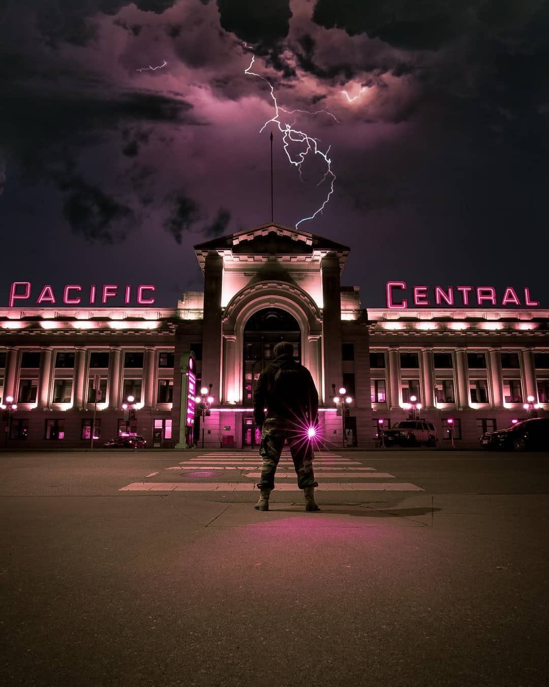 Silhouetted figure facing Pacific Central Station under a lightning-streaked Vancouver sky