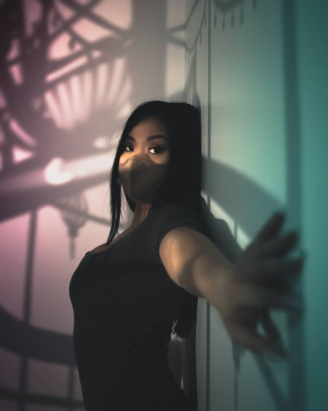 Masked portrait lit in pink and teal beneath a clock silhouette