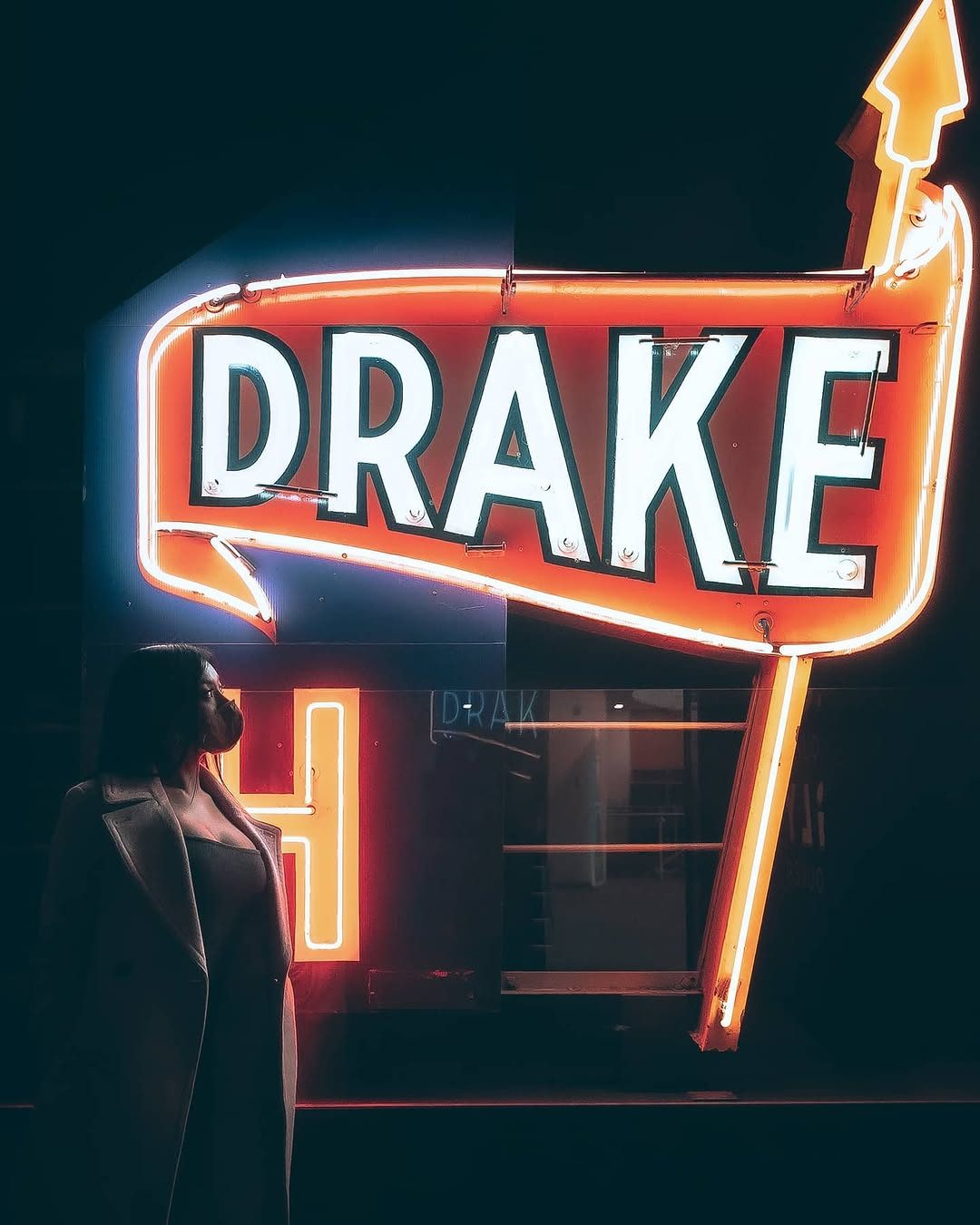 Silhouetted portrait beside a glowing neon hotel sign at night