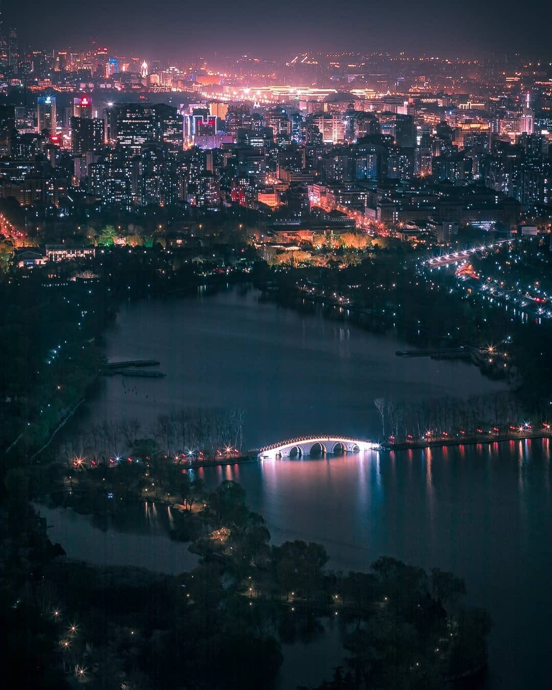 Aerial night view of a lantern-lit stone bridge over a lake in China