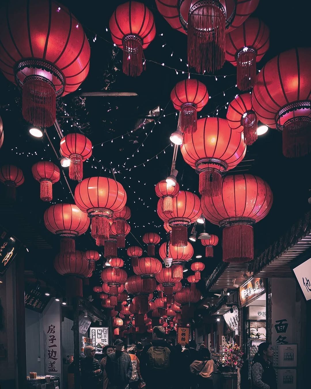 Rows of red lanterns glowing over a night market during Lunar New Year