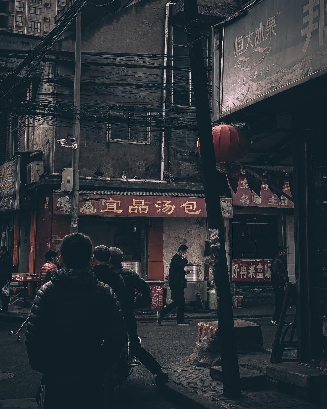 Gritty street corner with neon shop signs and tangled wires in China